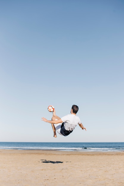 Guy voetballen op het strand