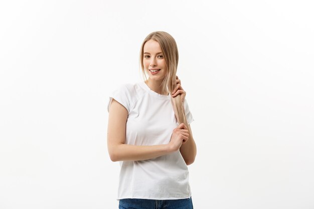 Haarverzorging. Jong Kaukasisch meisje dat haar met vinger kamt die op witte achtergrond wordt geïsoleerd