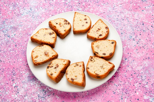 Half-bovenaanzicht cakeplakken met rozijnen in plaat op roze oppervlak cake bak zoete biscuit kleur taart suiker koekjes