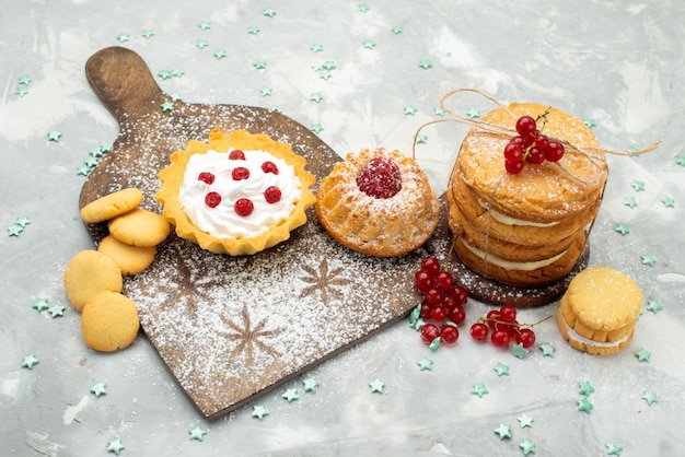 Half bovenaanzicht kleine d taarten met room en sandwichkoekjes op het lichte zoete oppervlak