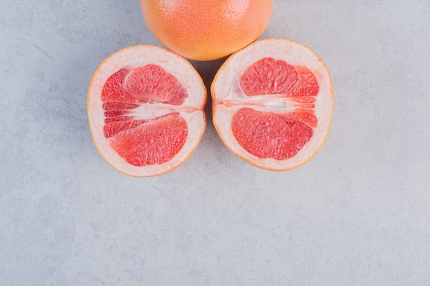 Half gesneden en hele grapefruit op grijze achtergrond.