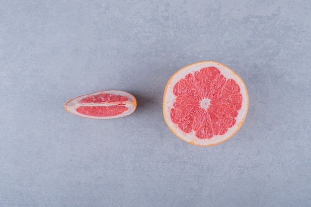 Half gesneden en plakje grapefruit op een grijze ondergrond