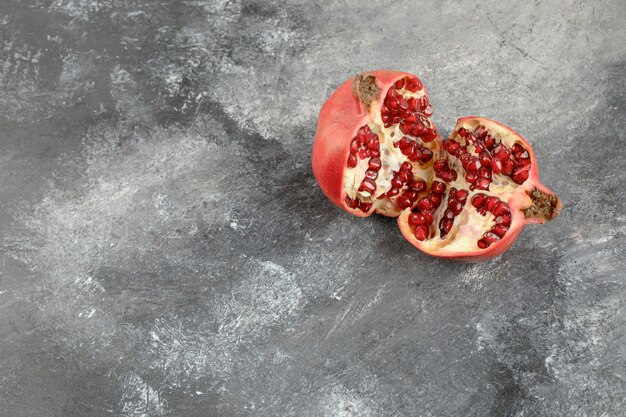 Half gesneden verse granaatappel op marmeren achtergrond.
