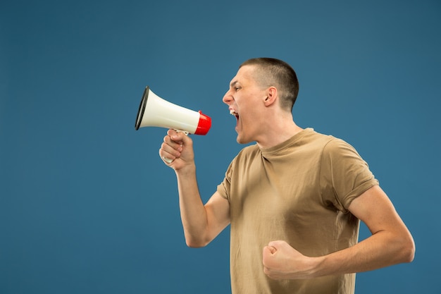 Gratis foto half-length portret van een blanke jonge man op blauwe studio