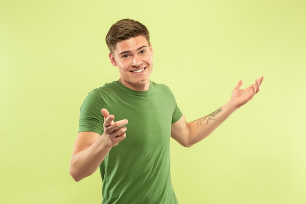 Half-length portret van een blanke jonge man op groene ruimte. Mooi mannelijk model in overhemd