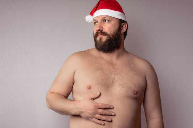 Half naakte bebaarde man met een kerstman hoed