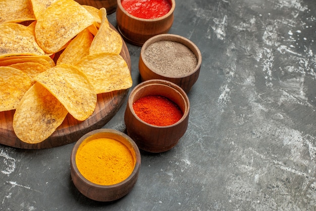 Half schot van chips, kruiden en mayonaise met ketchup op houten snijplank op grijze tafel