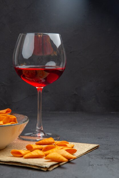 Half shot heerlijke chips binnen en buiten de kom en rode wijn in een glas op een oude krant