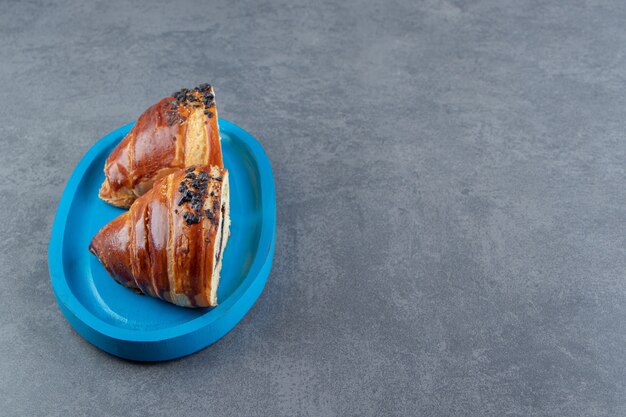 Halfgesneden smakelijke croissants met chocolade op blauw bord.