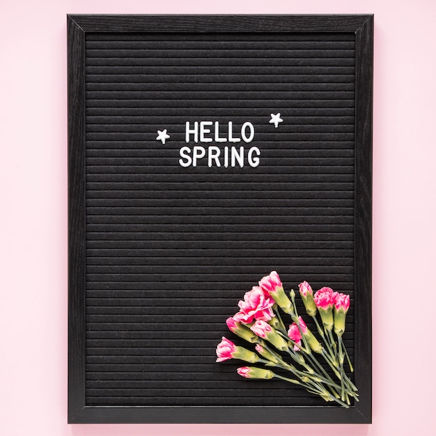 Hallo lente inscriptie met roze bloemen op een zwart bord