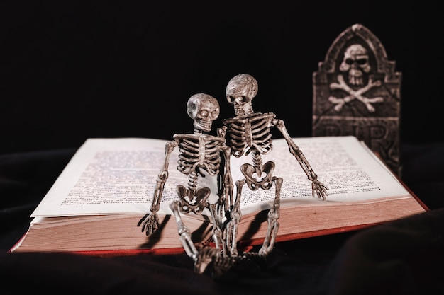 Halloween-concept met skelet op boek en grafsteen