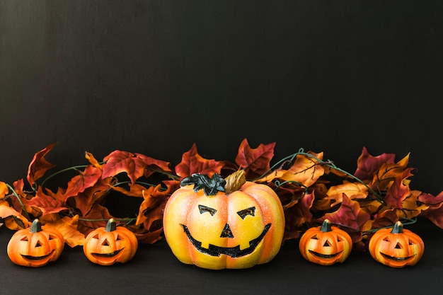 Halloween decoratie met vijf pompoenen en herfstbladeren