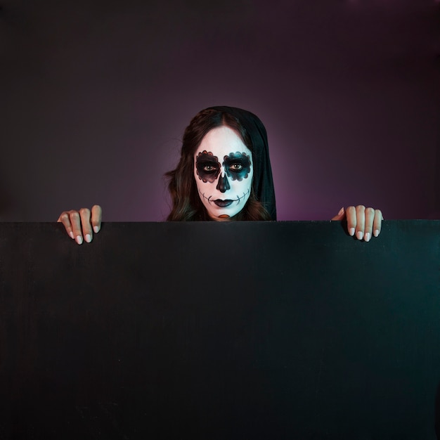 Gratis foto halloween meisje met make-up achter groot bord