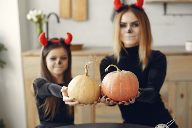 Halloween. Moeder en dochter in Halloween-kostuum. Familie thuis.