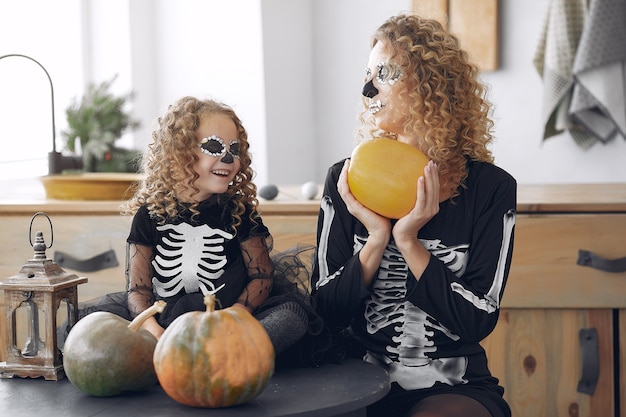 Halloween. moeder en dochter in halloween-kostuum in mexicaanse stijl. familie thuis met pompoenen.