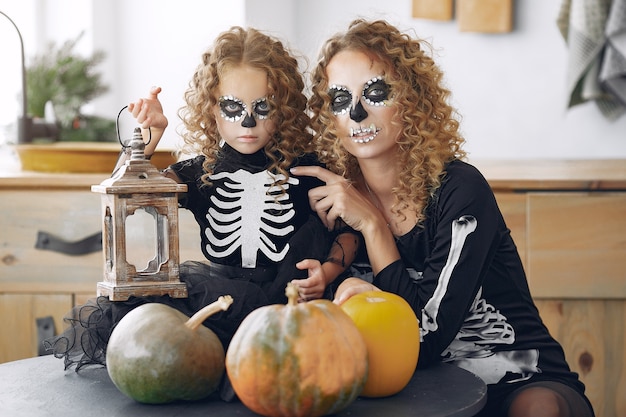 Halloween. moeder en dochter in halloween-kostuum in mexicaanse stijl. familie thuis met pompoenen.