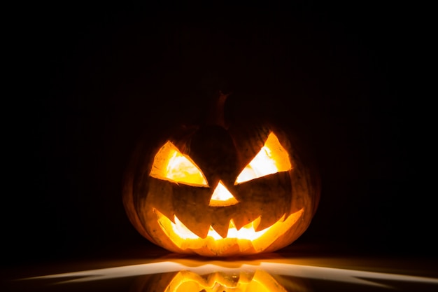 Halloween pompoen met licht binnen en op een zwarte achtergrond
