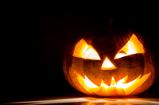 Halloween pompoen met licht binnen en op een zwarte achtergrond