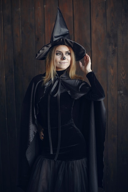 Halloween-samenstelling mooie vrouw met blond kapsel. Model meisje in zwart kostuum. Halloween-thema.