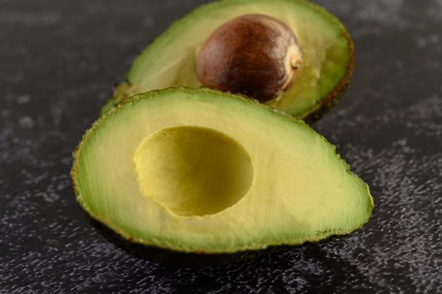 Gratis foto halve avocado op de zwarte cementvloer.