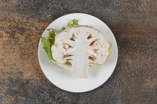 Halve bloemkool op het bord, op het marmeren oppervlak