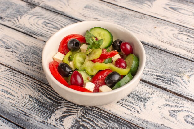 Halve bovenaanzicht verse groentesalade met gesneden komkommers tomaten olijf binnen plaat op het grijze oppervlak groente voedselsalade maaltijd kleur