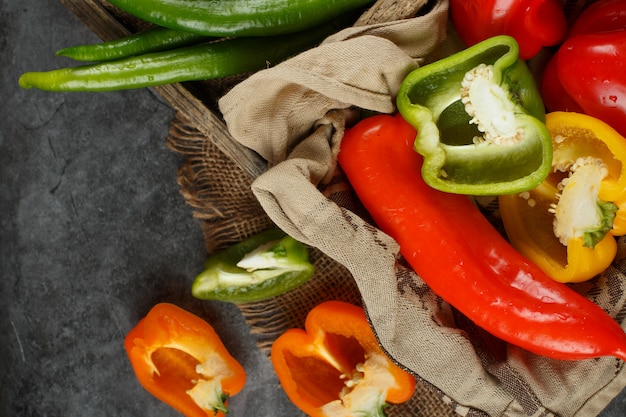 Halve en hele paprika's in en uit een houten bakje.