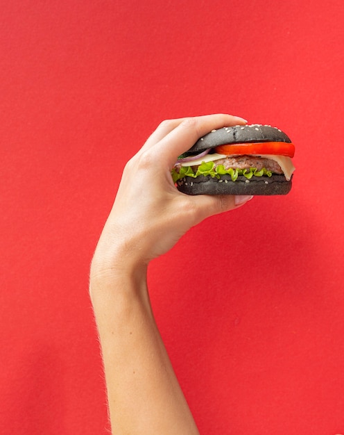 Hamburger die voor rode achtergrond wordt gehouden