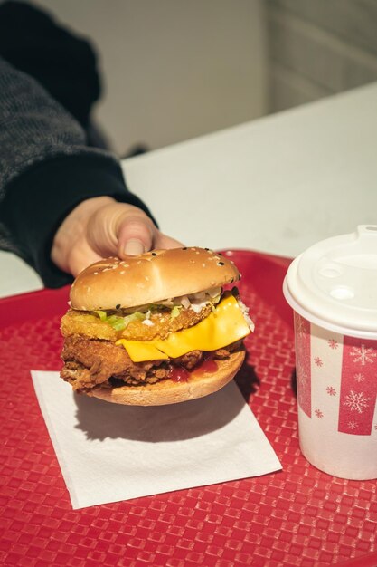 Gratis foto hamburger met gebakken kip in een fastfoodcafé in vrouwelijke handen