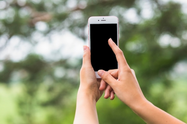 Hand aanraken van het scherm van mobiel in openlucht