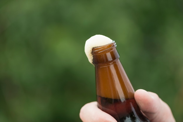 Hand bijsnijden met geopende fles bier