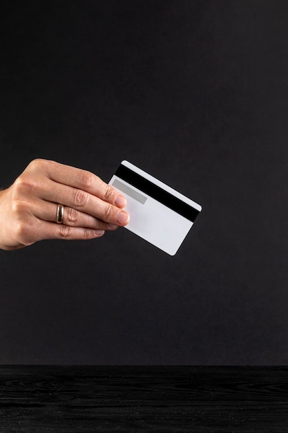 Hand die een creditcard op zwarte achtergrond houdt