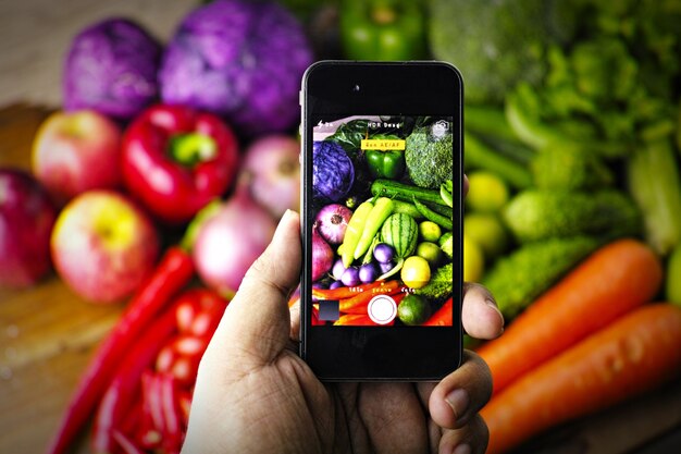 Hand die een telefoon en fotograferen groenten