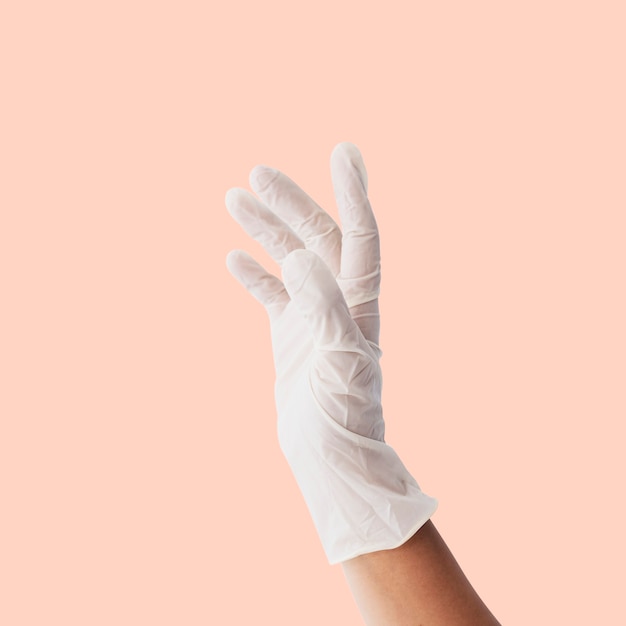 Hand die een witte latexhandschoen draagt om besmetting met het coronavirus te voorkomen