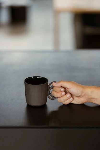 Hand die een zwarte koffiekop op een zwarte lijst houdt