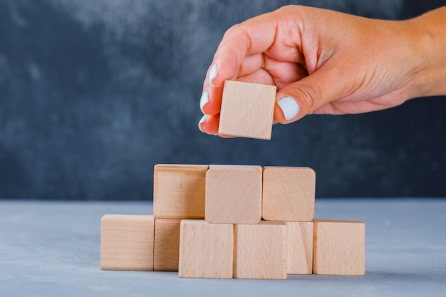 Hand die en houten kubussen zet stapelt