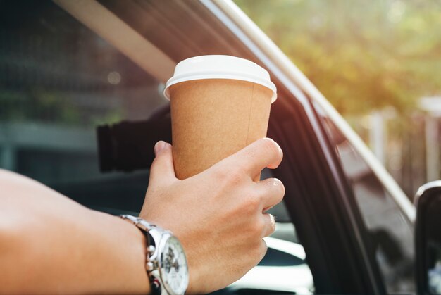 Hand die meeneemkoffie in een auto houdt