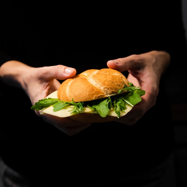 Gratis foto hand die smakelijk ongezuurd broodje met sla houdt