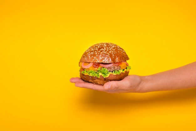 Hand die smakelijke rundvleeshamburger houdt