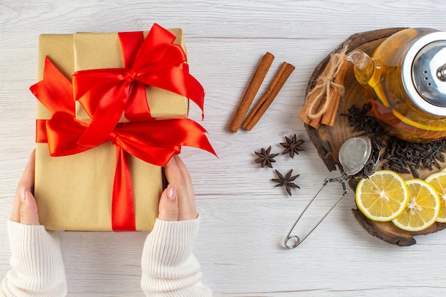 Hand met cadeau met rood lint zwarte thee met citroen