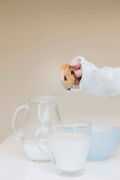 Hand met cookie over melk