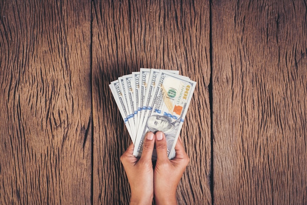 Gratis foto hand met dollar bankbiljet geld op hout achtergrond