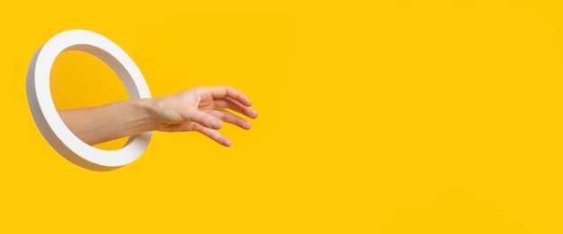 Hand met een rond gat pakt een onzichtbaar object op een gele achtergrond. banier. Premium Foto