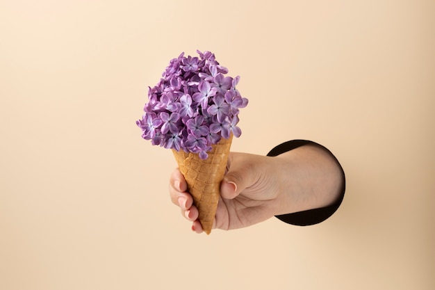 Hand met ijshoorntje met bloemen