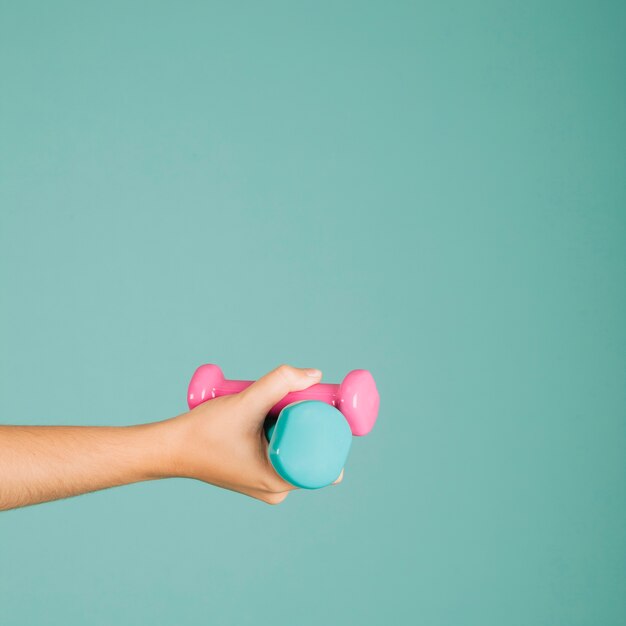 Hand met kleurrijke dumbbells