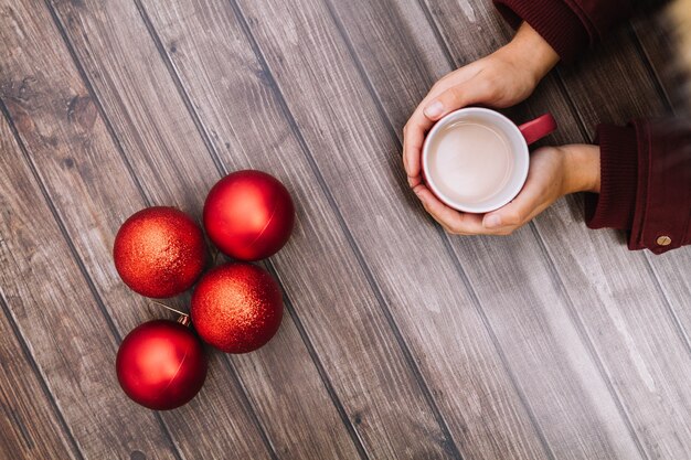 Hand met koffie en kerstballen