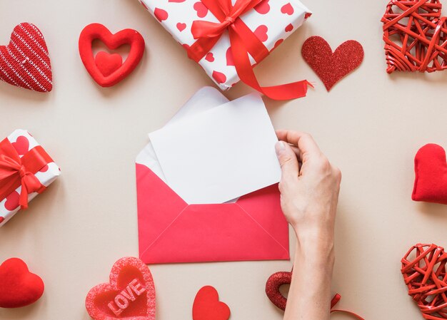 Hand met papier in de buurt van de envelop, presenteert en sieraad harten