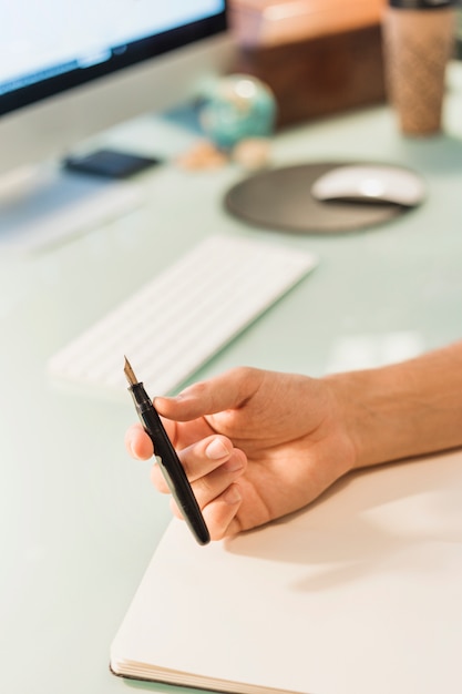 Hand met pen op het bureau