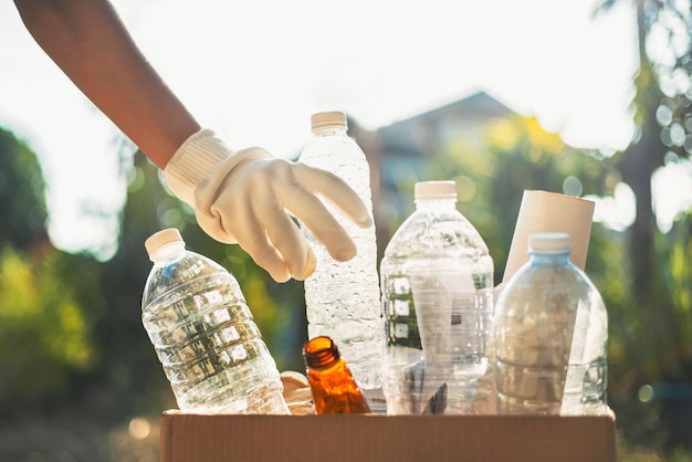 Hand met plastic afvalfles die in een recyclezak wordt gedaan om schoon te maken