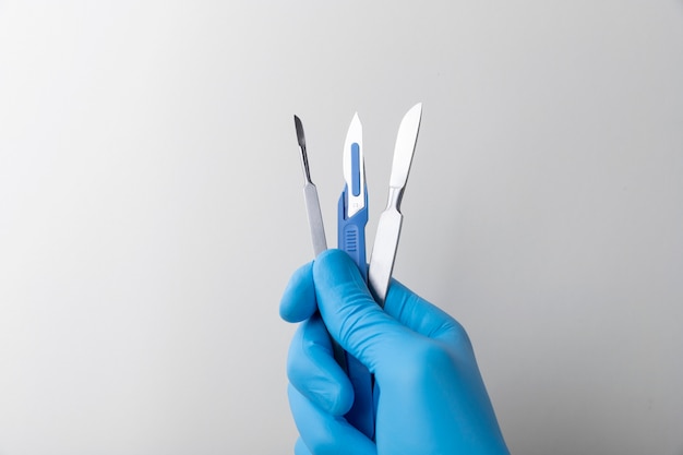 Hand met rubberen handschoen met medische scalpel